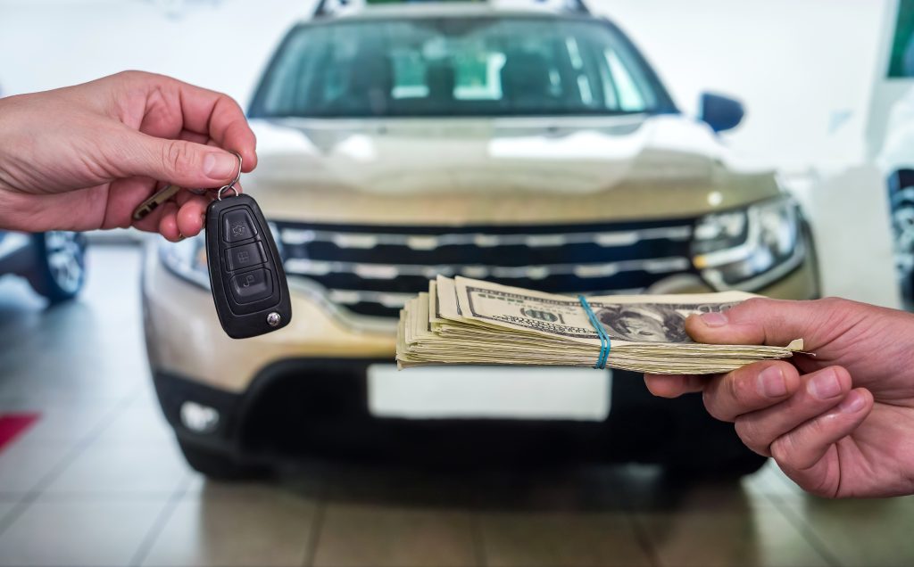 businessman purchase new car in showroom giving dollars money and taking keys from car
